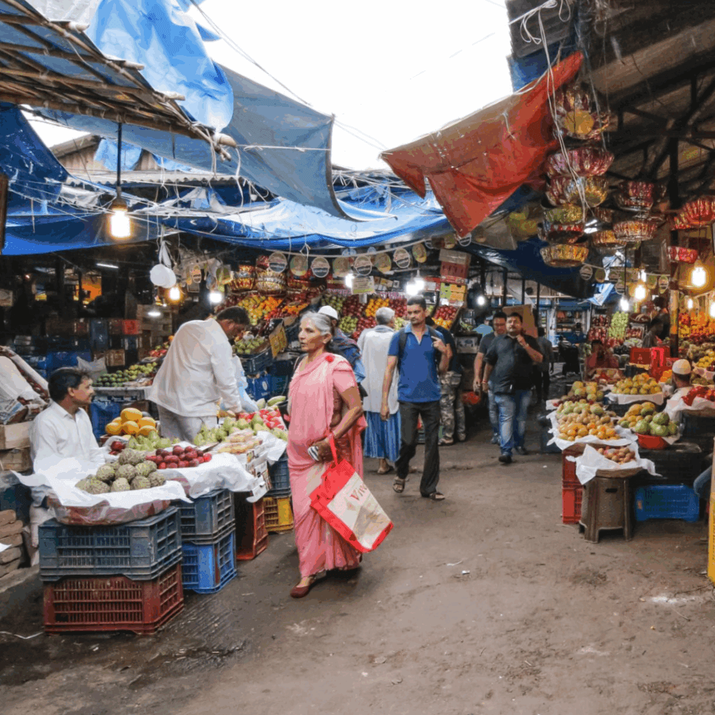 Busy Crawford Market interior in Mumbai with vendors selling fresh produce under blue tarps