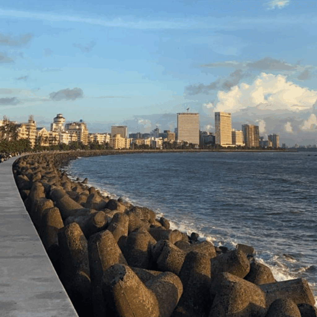 View of Marine Drive promenade in Mumbai with city skyline and sea waves during sunset.